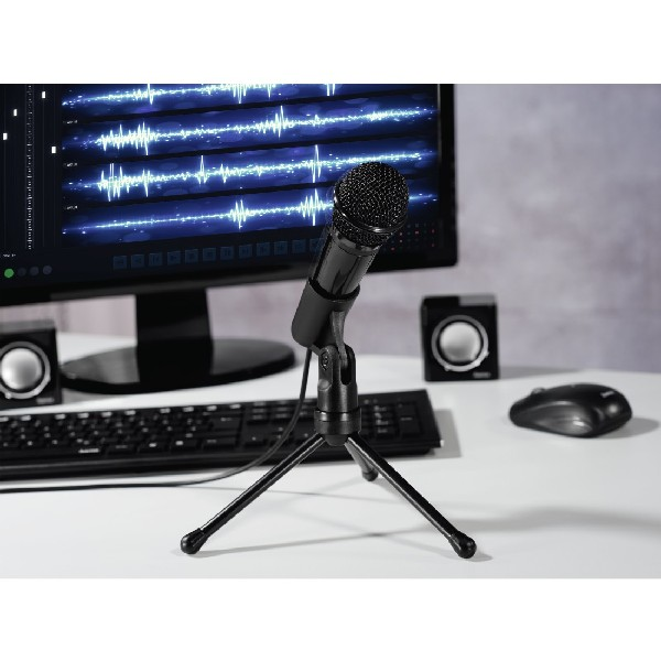 Micrófono negro en trípode frente a monitor con patrones de ondas de sonido. Altavoces y ratón.
