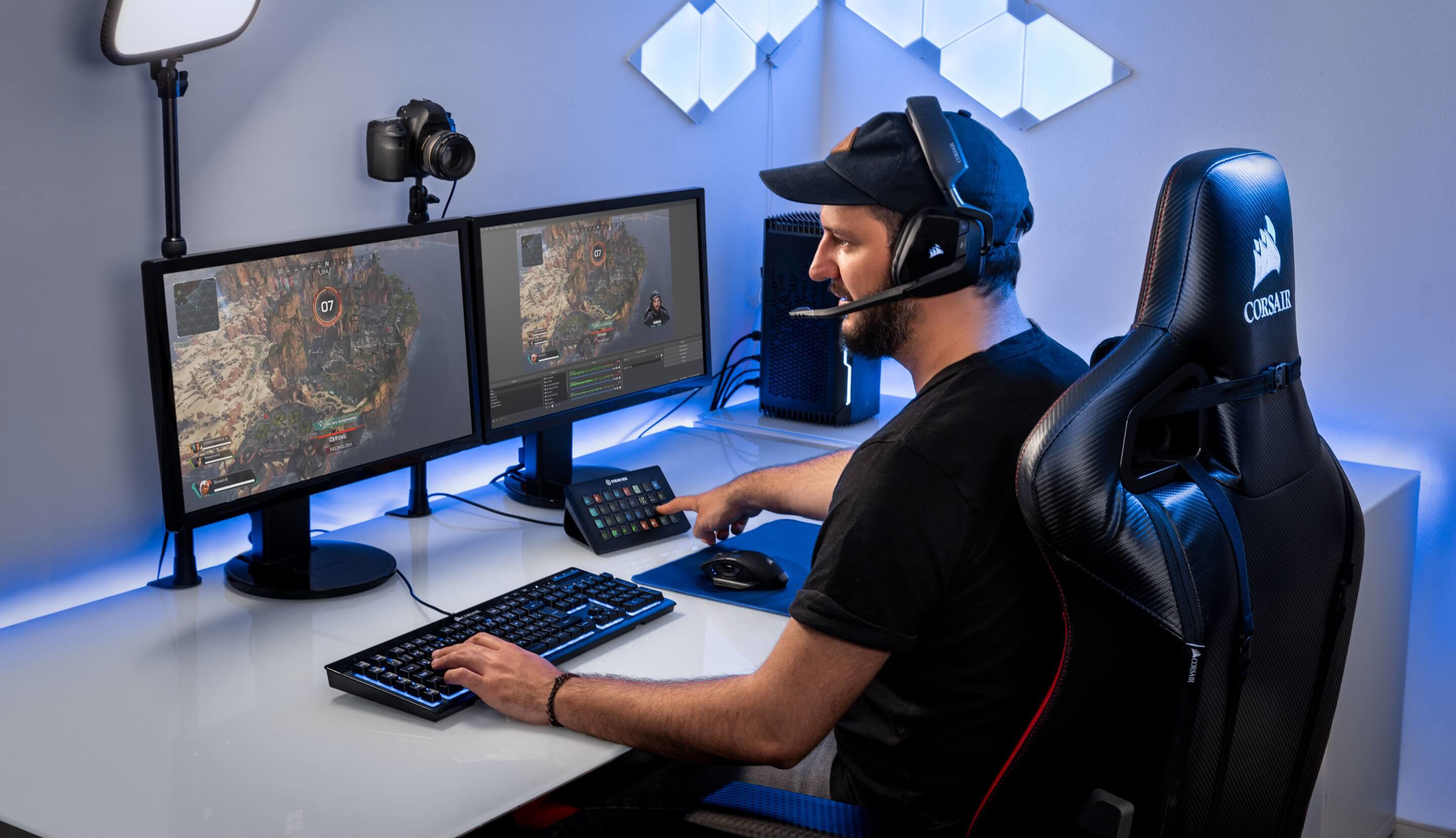Gamer an einem Schreibtisch. Monitore zeigen Gameplay. Tastatur, Headset und Stream Deck sind sichtbar.