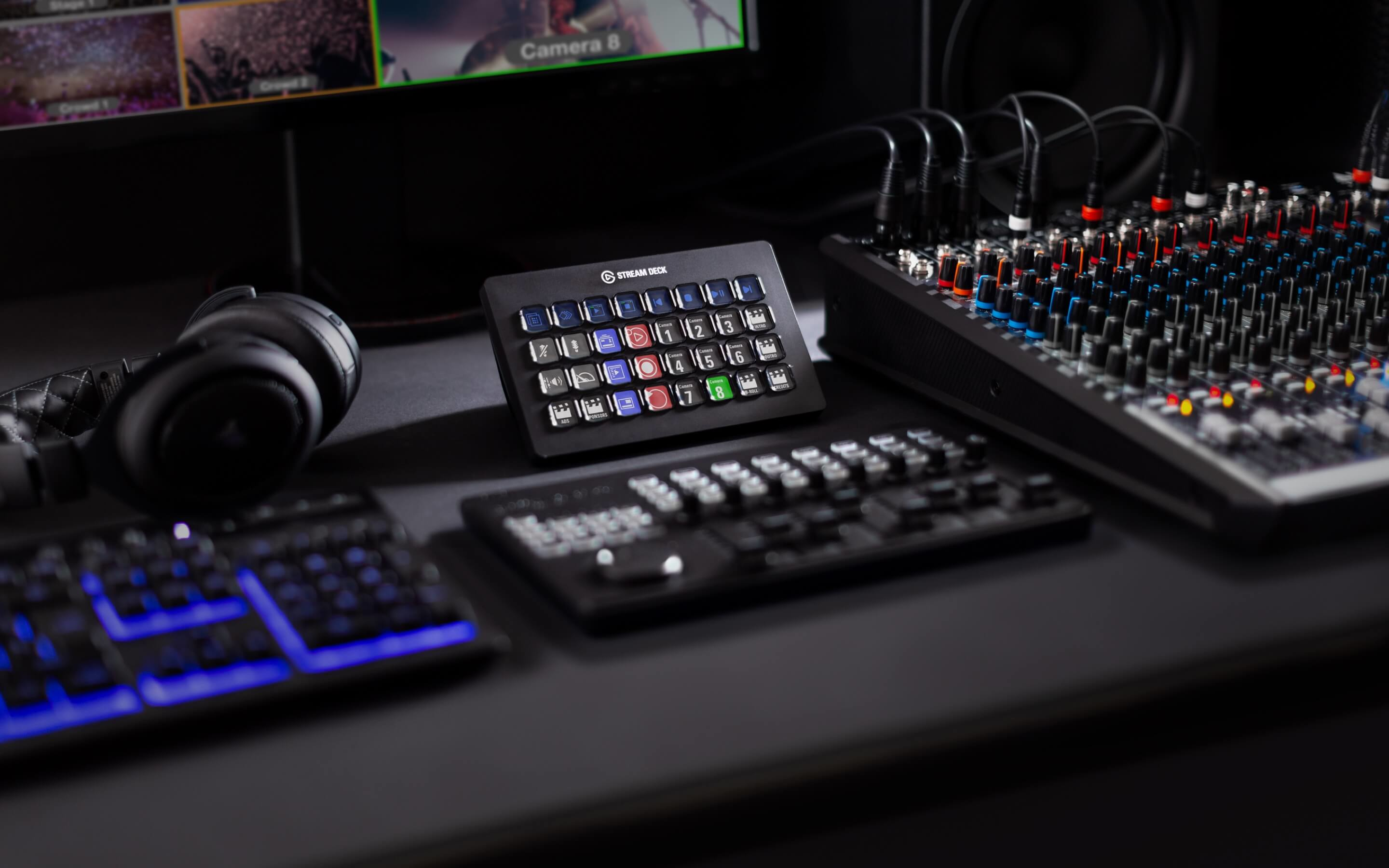 Stream Deck Controller mit mehreren Knöpfen, und Audioausrüstung im Hintergrund.