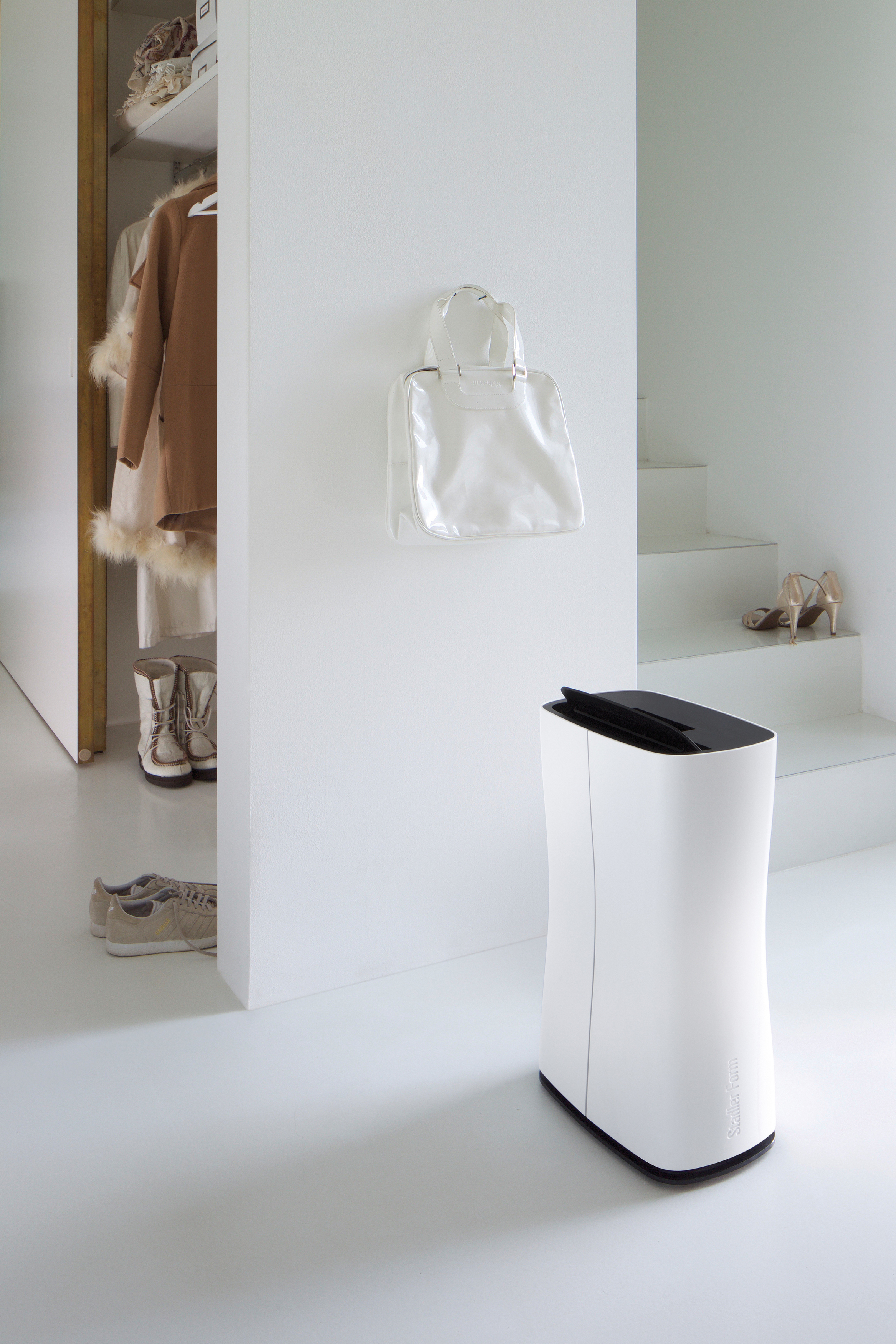 Weißes Zimmer mit weißem Schrank, Tasche und Luftreiniger.