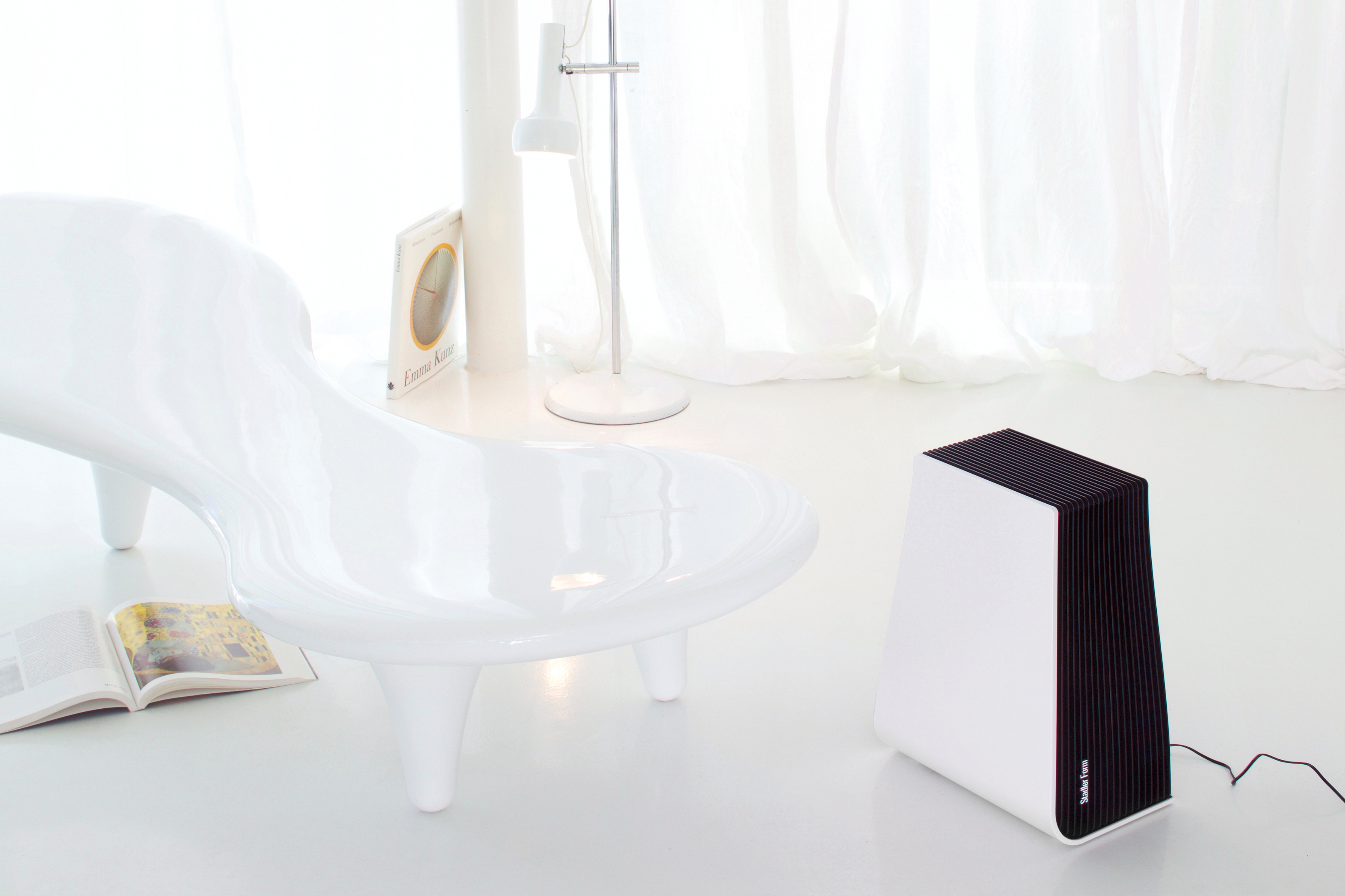 Modernes weißes Zimmer mit Stuhl, Lampe und einem schwarz-weißen Luftreiniger.