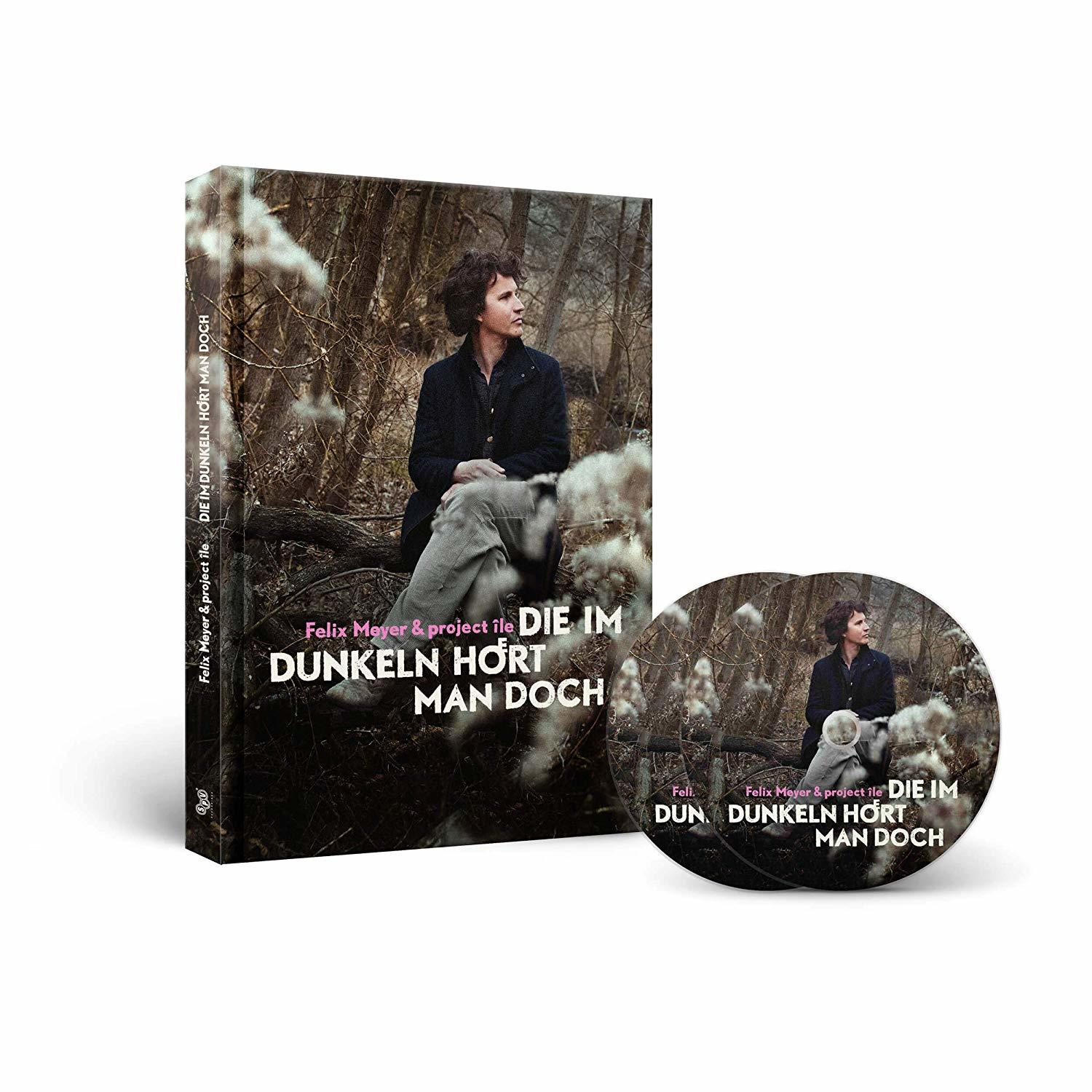 Ein Buch und eine CD mit einer Person, die in einem Wald auf einem Baumstamm sitzt.