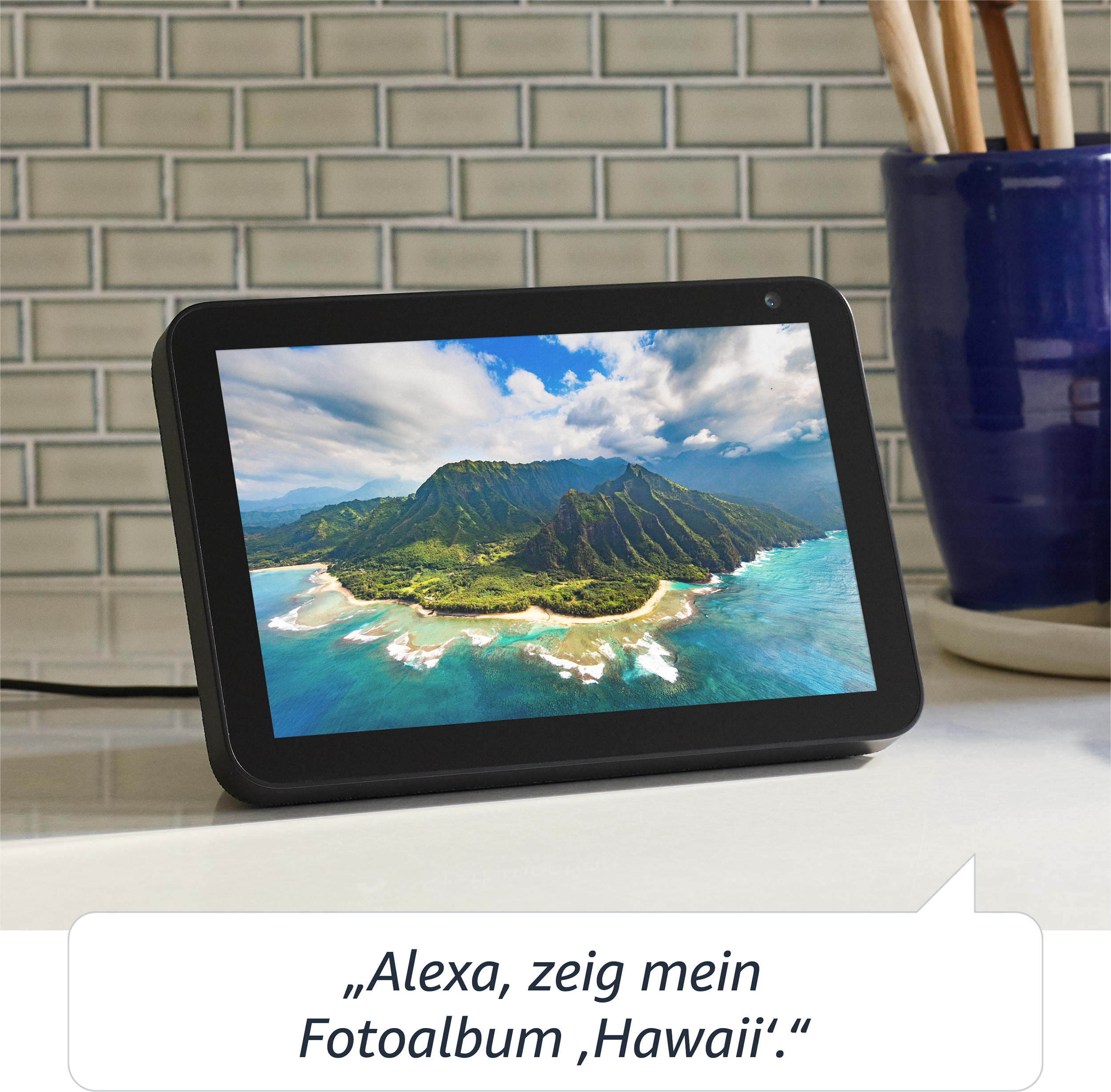 Schwarzes Smart-Display, das eine tropische Landschaft zeigt. Eine Sprechblase lautet: „Alexa, zeig mein Hawaii-Album.“